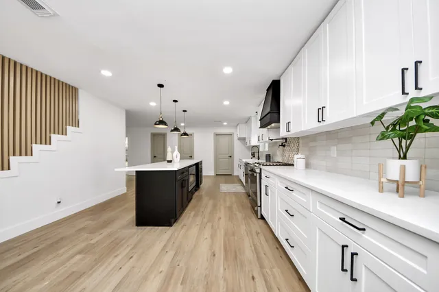 a large kitchen with stainless steel appliances sink a microwave and wooden floor