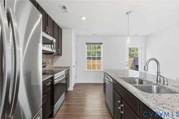 a kitchen with stainless steel appliances granite countertop a sink stove and refrigerator