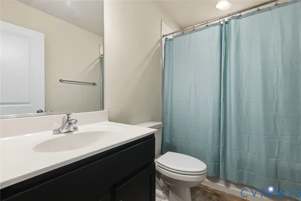 a bathroom with a sink a toilet a mirror and shower curtain
