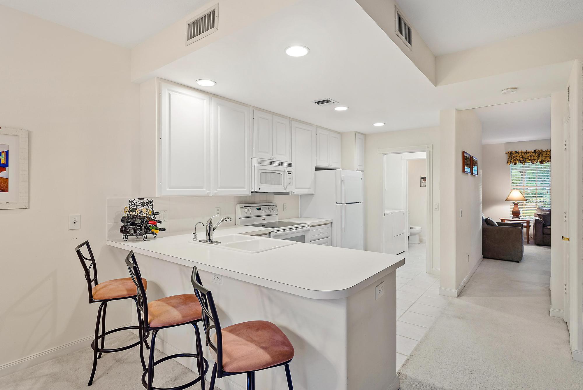 277 New Haven Boulevard Jupiter, FL 33458 - Photo 18 of 36 a kitchen with a dining table chairs refrigerator and cabinets
