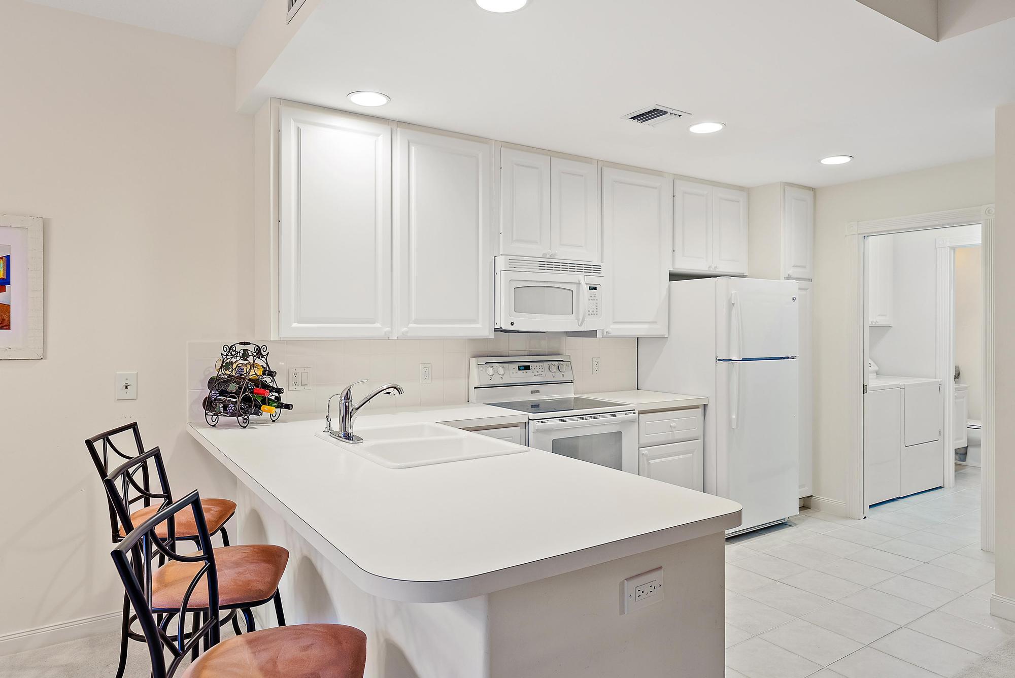 277 New Haven Boulevard Jupiter, FL 33458 - Photo 19 of 36 a white kitchen with a stove a sink and white cabinets with wooden floor