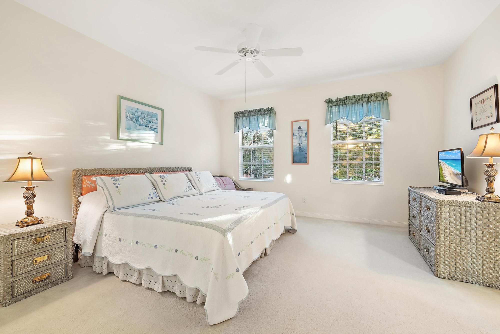 277 New Haven Boulevard Jupiter, FL 33458 - Photo 27 of 36 a spacious bedroom with a large bed and a chandelier