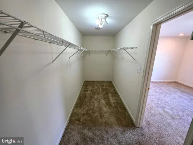 a view of a hallway with a white walls stairs and a chandelier