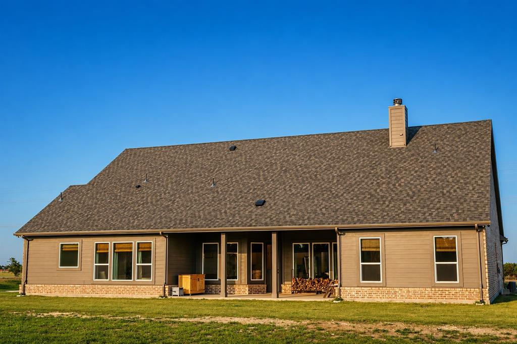 1530 County Road 200 Valley View, TX 76272 - Photo 33 of 34 Rear exterior featuring a covered patio, multiple windows, a shingled roof, a chimney, and a brick base