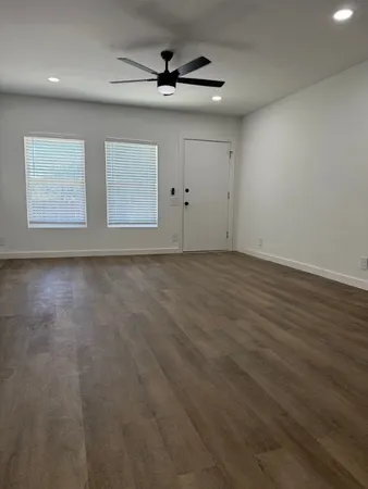 an empty room with windows and ceiling fan