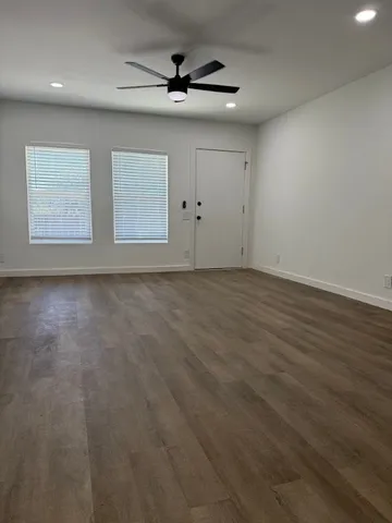 an empty room with windows and ceiling fan
