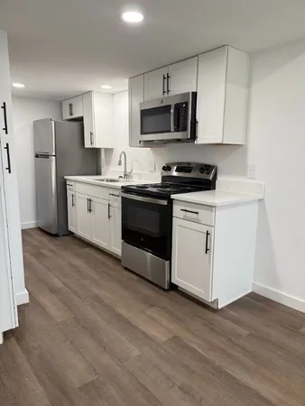 a kitchen with stainless steel appliances a sink a stove a microwave and cabinetry