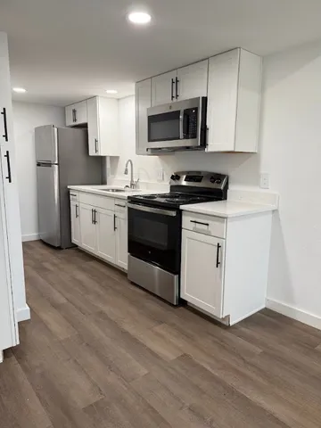 a kitchen with stainless steel appliances a sink a stove a microwave and cabinetry