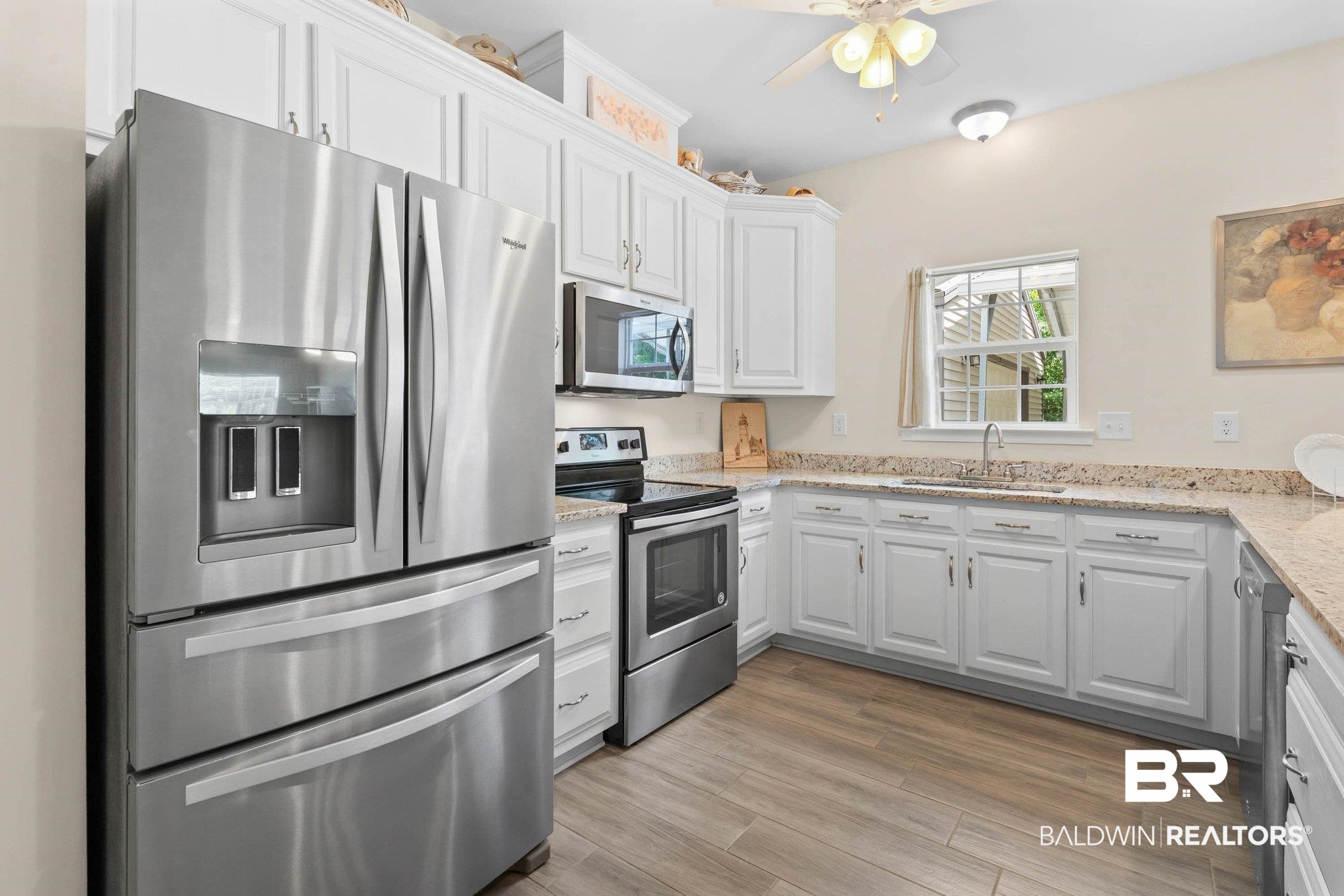 13751 Fish River Acres Circle Foley, AL 36535 - Photo 10 of 26 Kitchen featuring stainless steel appliances, white cabinetry with crown molding, light-toned countertops, wood-finish flooring, and a window above the sink