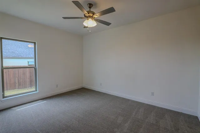 an empty room with a window and a fan