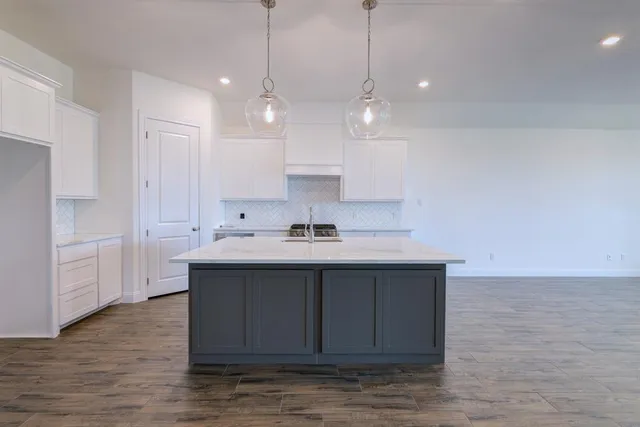 a view of a kitchen with kitchen island a sink stainless steel appliances and cabinets