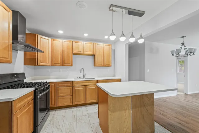 a kitchen with a sink a center island a stove cabinets and wooden floor