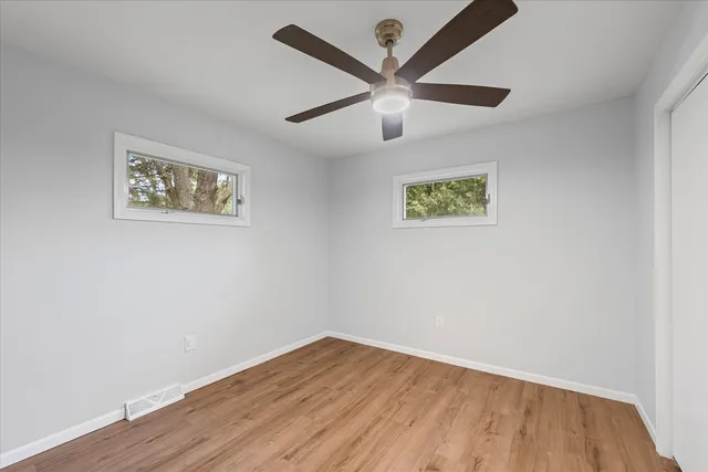 an empty room with wooden floor and ceiling fan