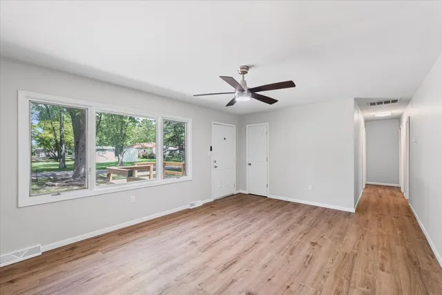 a view of a big room with wooden floor and windows