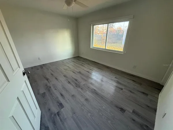 an empty room with wooden floor and windows