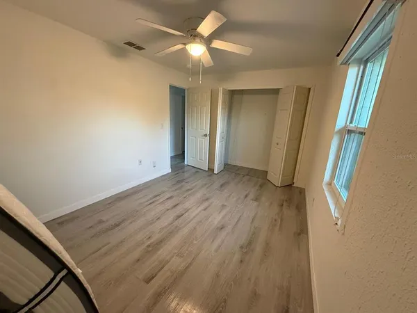a view of empty room with wooden floor and fan