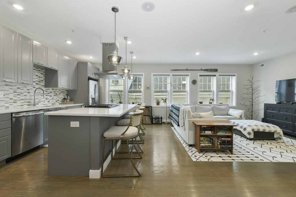 47 Sargent Street, Unit 3 Boston, MA 02125 - Photo 4 of 21 a large kitchen with stainless steel appliances kitchen island granite countertop a large center island attached withe living room
