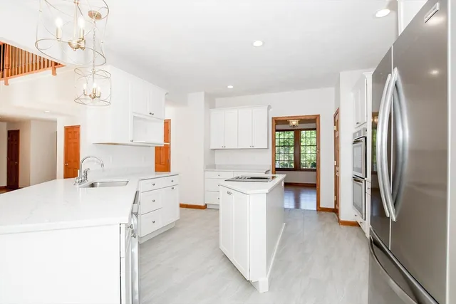 a kitchen that has a lot of white cabinets and stainless steel appliances