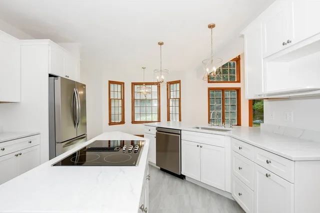 a kitchen that has a lot of white cabinets and stainless steel appliances