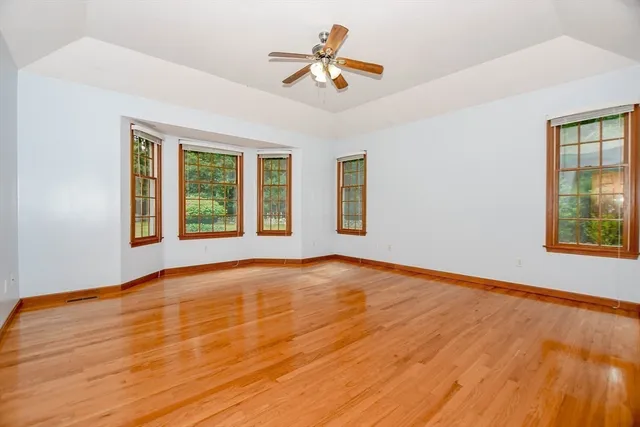 a view of an empty room with window and wooden floor