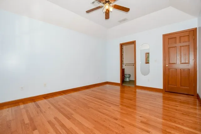 an empty room with wooden floor fan and windows