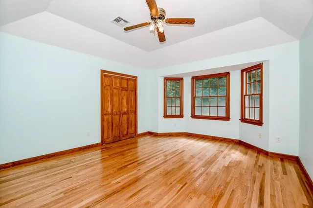 a view of an empty room with window and wooden floor