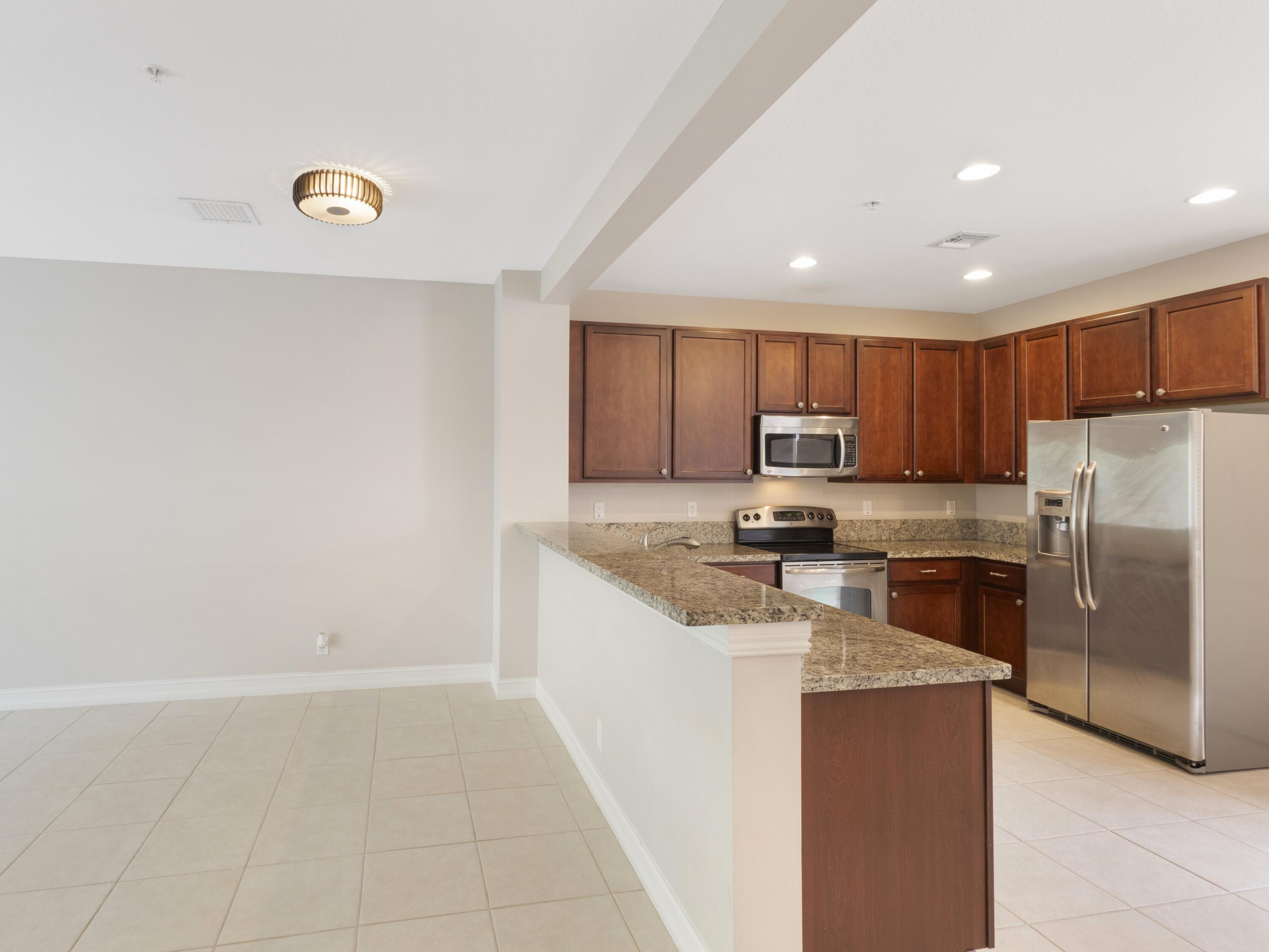 110 West Coda Circle, Unit 110 Delray Beach, FL 33444 - Photo 12 of 42 a kitchen with granite countertop a refrigerator and a stove top oven