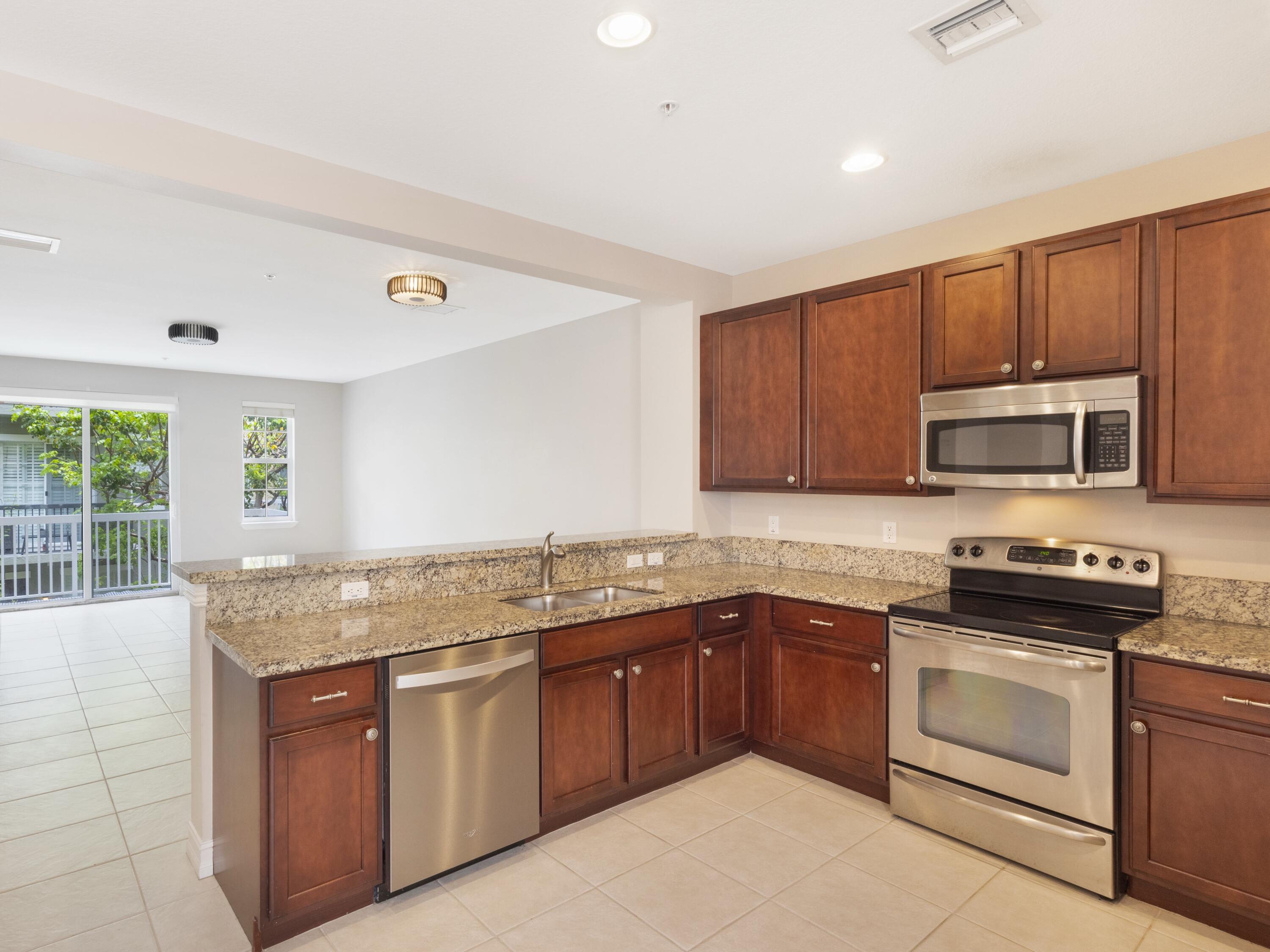 110 West Coda Circle, Unit 110 Delray Beach, FL 33444 - Photo 13 of 42 a kitchen with stainless steel appliances granite countertop a stove sink and microwave