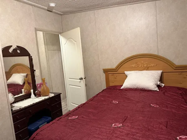a bedroom with a bed and a dresser with mirror