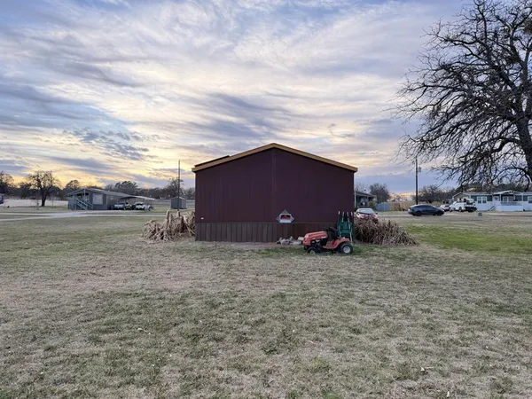 a view of a barn house next to a yard with large trees