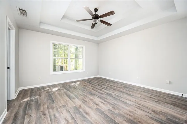 an empty room with wooden floor fan and windows