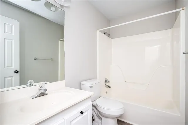 an empty room with wooden floor ceiling fan and windows