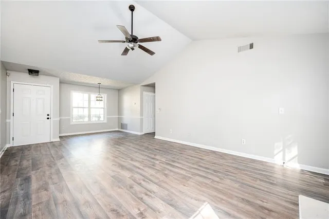 an empty room with wooden floor cabinet and windows