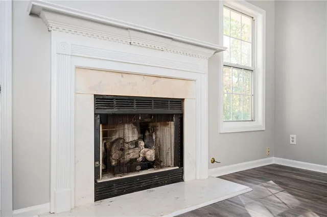 an empty room with wooden floor fireplace and windows