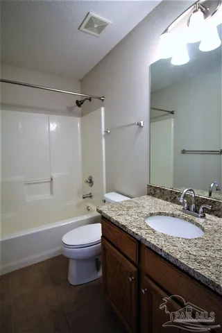 a bathroom with a granite countertop sink a toilet a mirror and bathtub