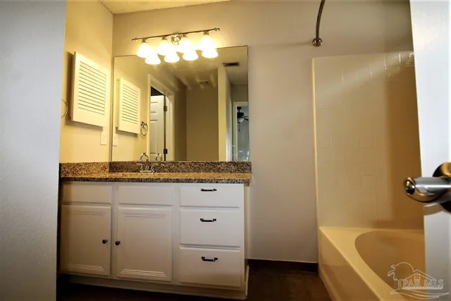 a bathroom with a granite countertop sink and a bathtub