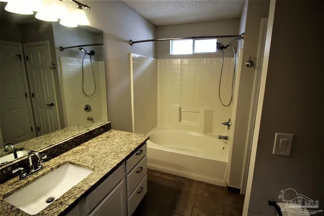 a bathroom with a granite countertop sink a mirror and a bathtub