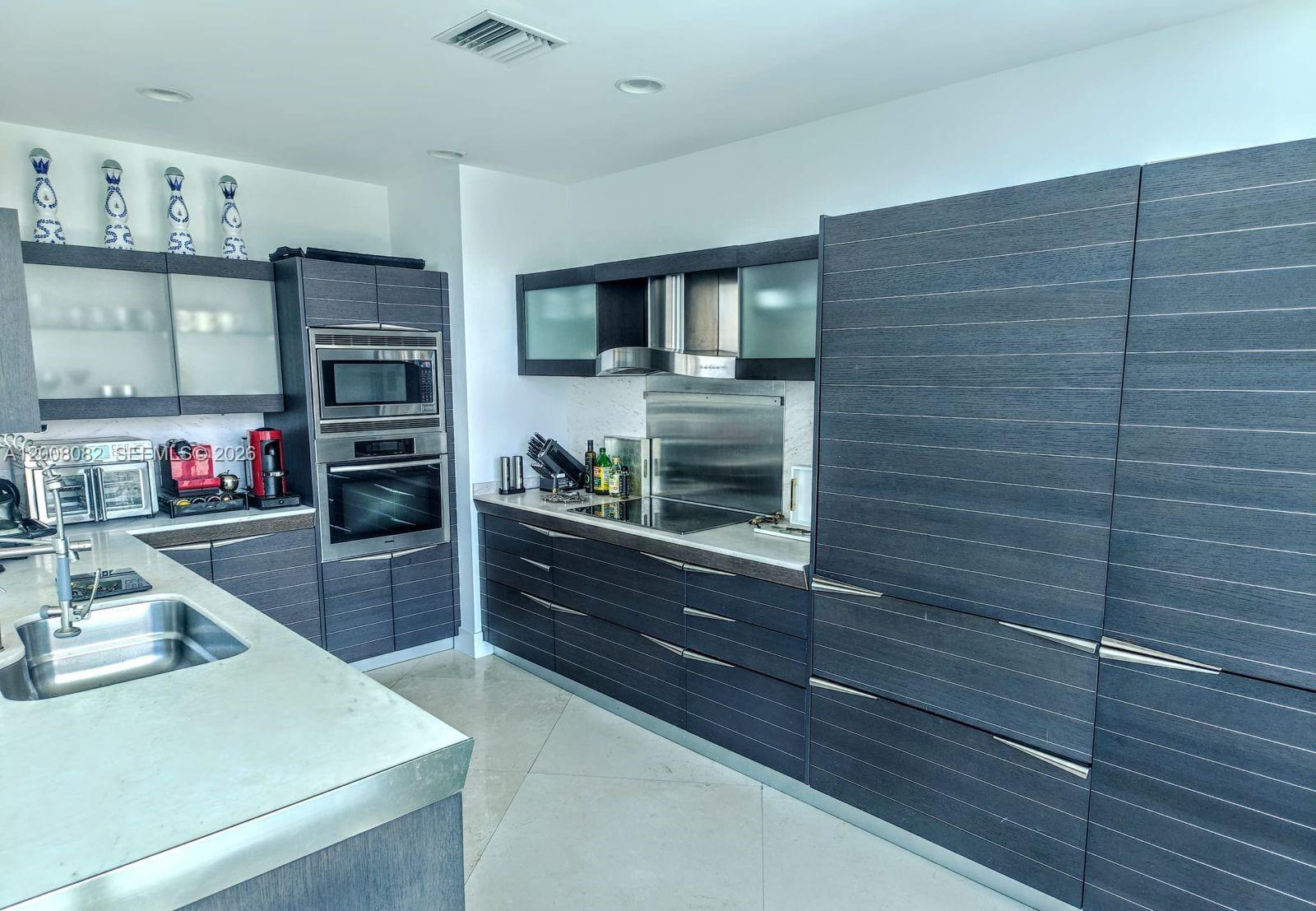 200 Biscayne Blvd Way, Unit 5001 Miami, FL 33131 - Photo 13 of 53 a kitchen with stainless steel appliances wooden cabinets and a stove top oven