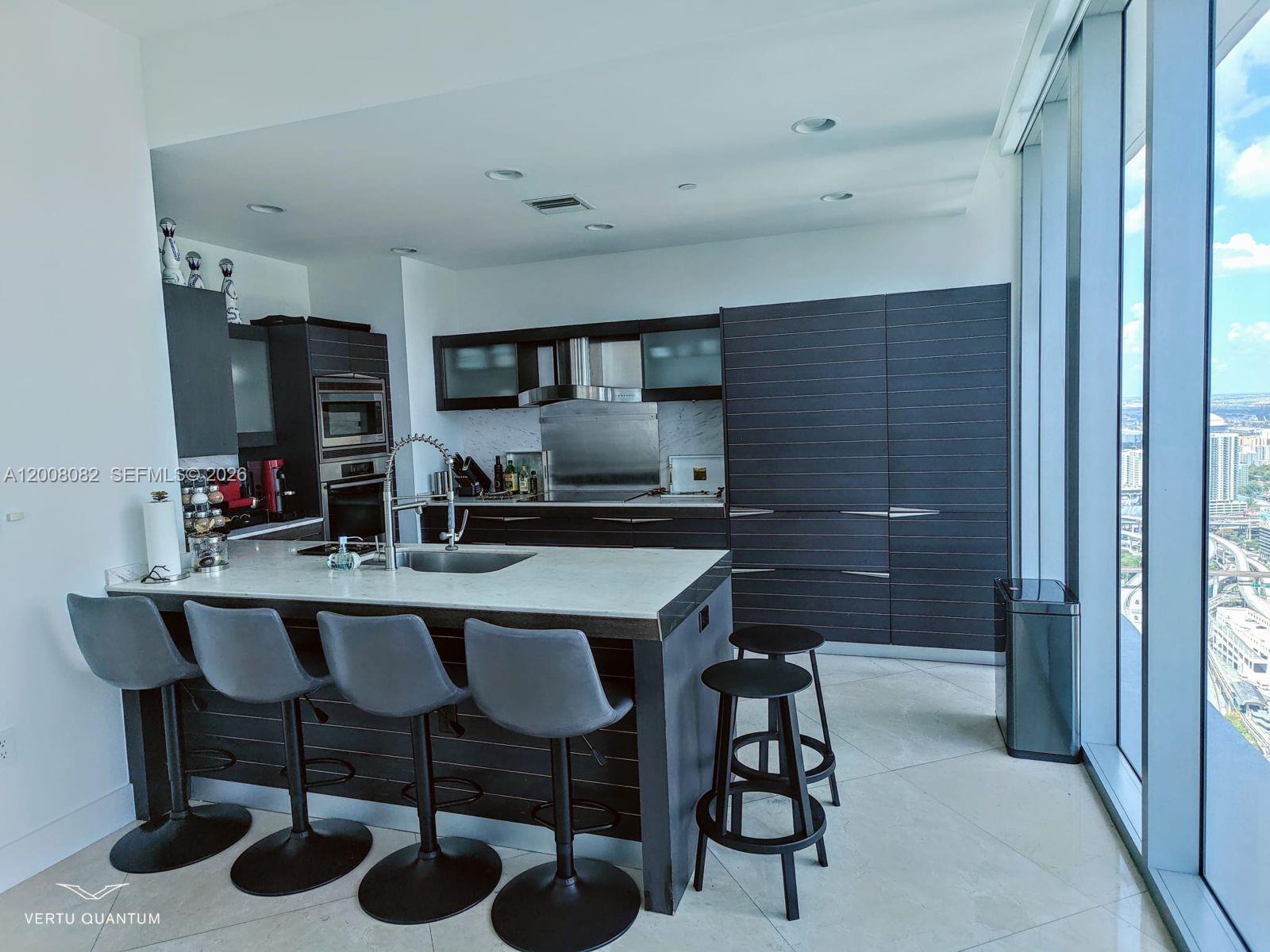 200 Biscayne Blvd Way, Unit 5001 Miami, FL 33131 - Photo 10 of 53 a white kitchen with a sink and chairs
