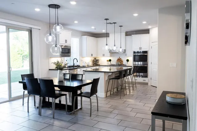 a kitchen with granite countertop a dining table chairs and white cabinets