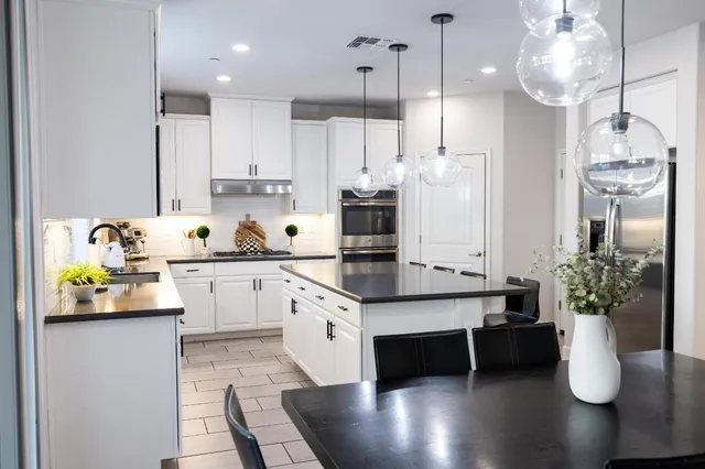 a kitchen with stainless steel appliances granite countertop a refrigerator a sink dishwasher and white cabinets with wooden floor