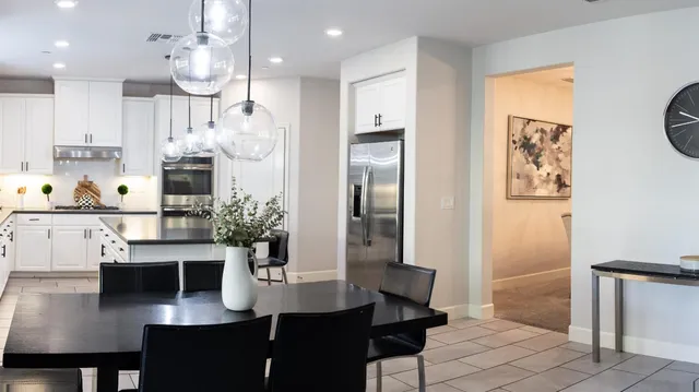 a room with stainless steel appliances a dining table chairs and kitchen view