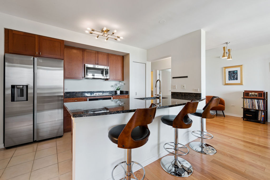 807 Davis Street, Unit 1907 Evanston, IL 60201 - Photo 7 of 20 a kitchen with stainless steel appliances kitchen island granite countertop a refrigerator and a view of living room