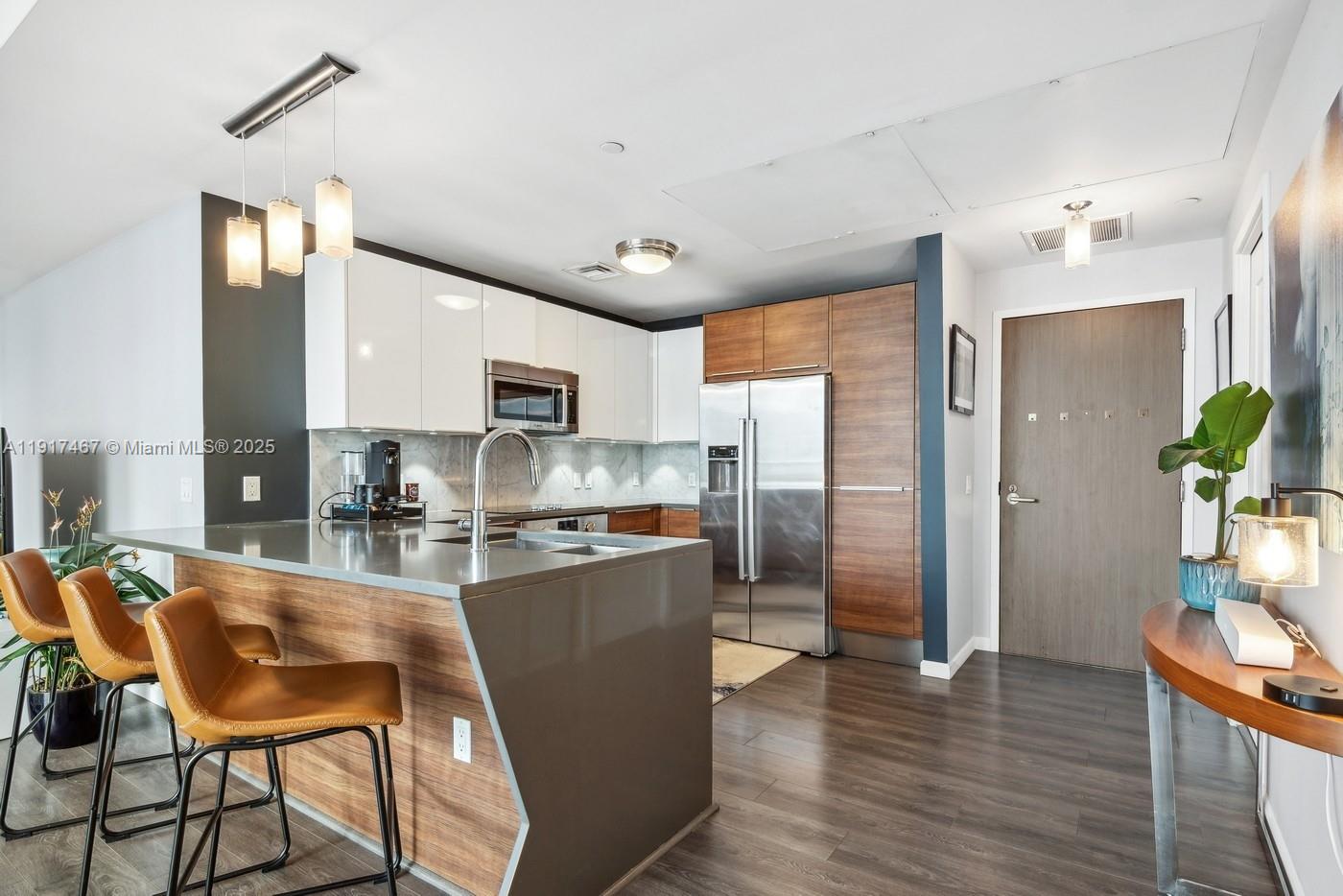 601 Northeast 27th Street, Unit 1406 Miami, FL 33137 - Photo 4 of 13 a kitchen with stainless steel appliances granite countertop a refrigerator a stove top oven a sink dishwasher and white cabinets with wooden floor