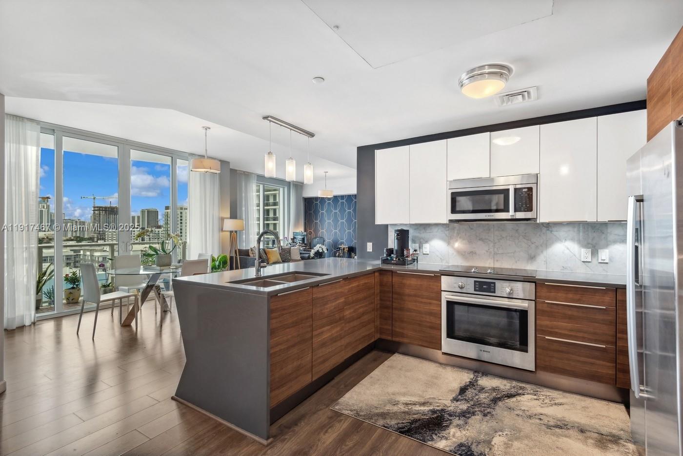 601 Northeast 27th Street, Unit 1406 Miami, FL 33137 - Photo 5 of 13 a kitchen with stainless steel appliances granite countertop a stove top oven a sink dishwasher a dining table and chairs with wooden floor