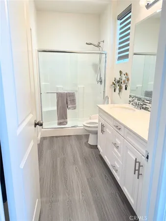 a bathroom with a double vanity sink a toilet and shower