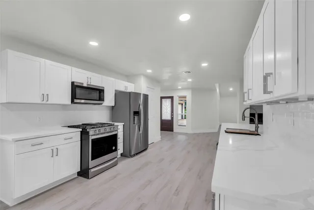 a kitchen with stainless steel appliances a refrigerator a stove top oven and a sink