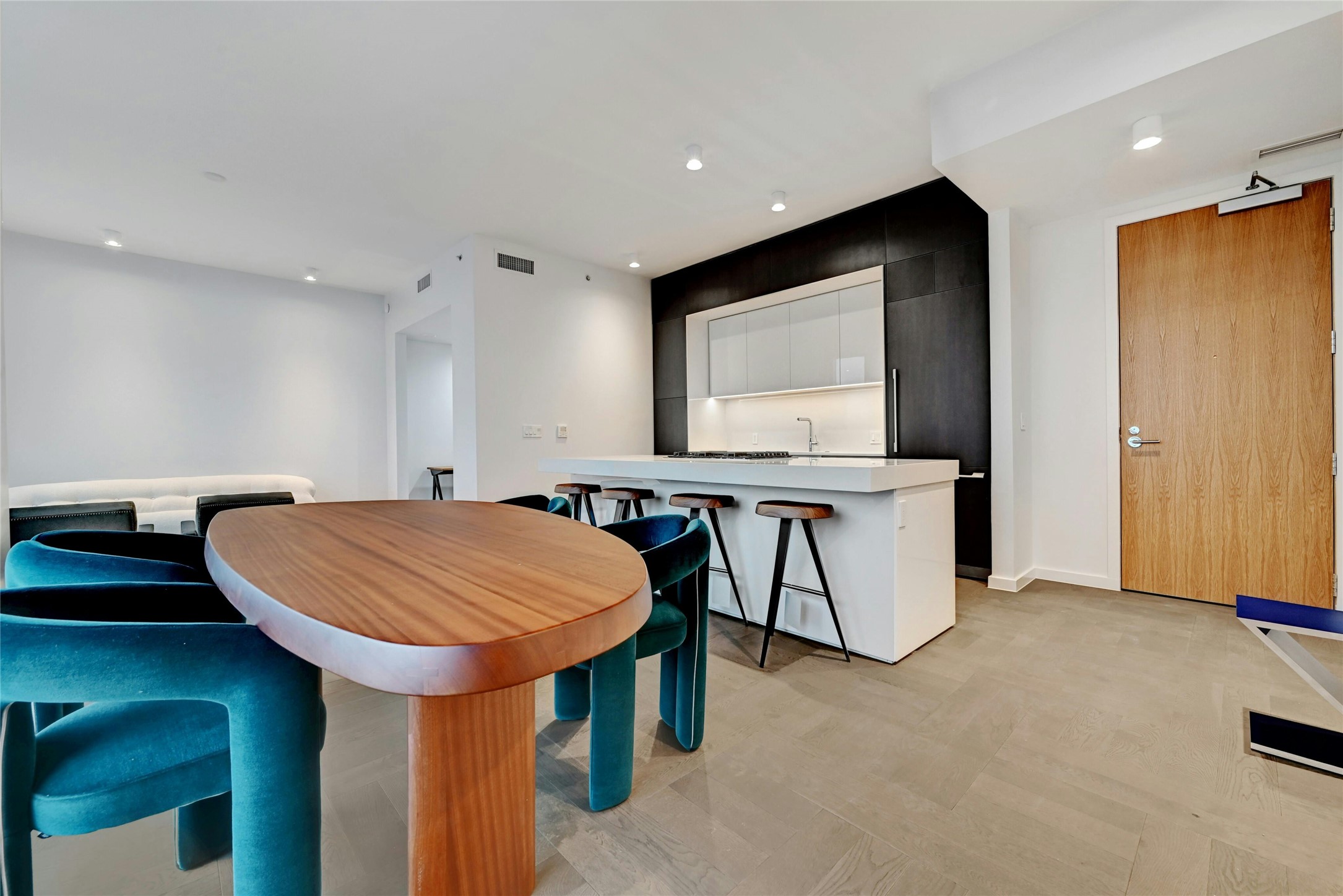 313 West 17th Street, Unit 2306 Austin, TX 78701 - Photo 3 of 35 A modern, open-concept kitchen, dining and living area. The kitchen features a sleek, minimalist design with a large island at its center, topped with white-colored stone countertop. The island includes a built-in gas cooktop and stainless steel oven. Furnishings provided by Scott + Cooner available for purchase separately.