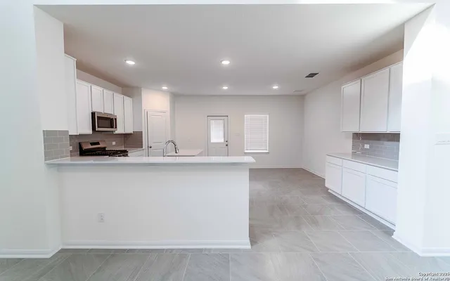 a view of kitchen with stainless steel appliances cabinets and a window