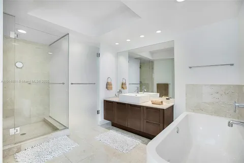 a spacious bathroom with a tub sink shower and mirror